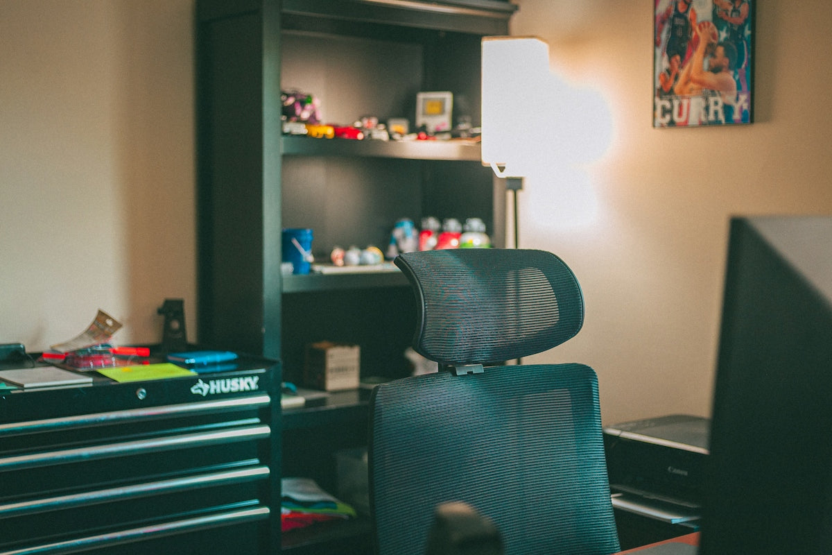 Organized home office with black furniture and bright lamp
