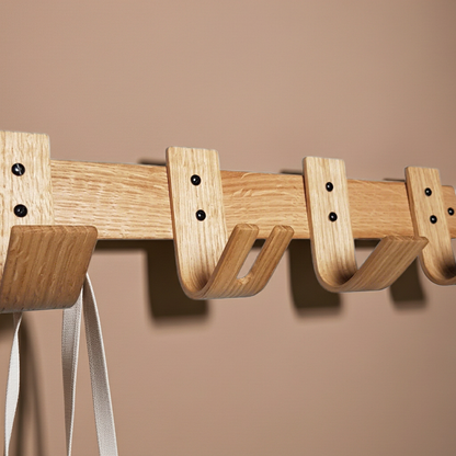 Wooden wall-mounted coat rack with hooks on a beige background